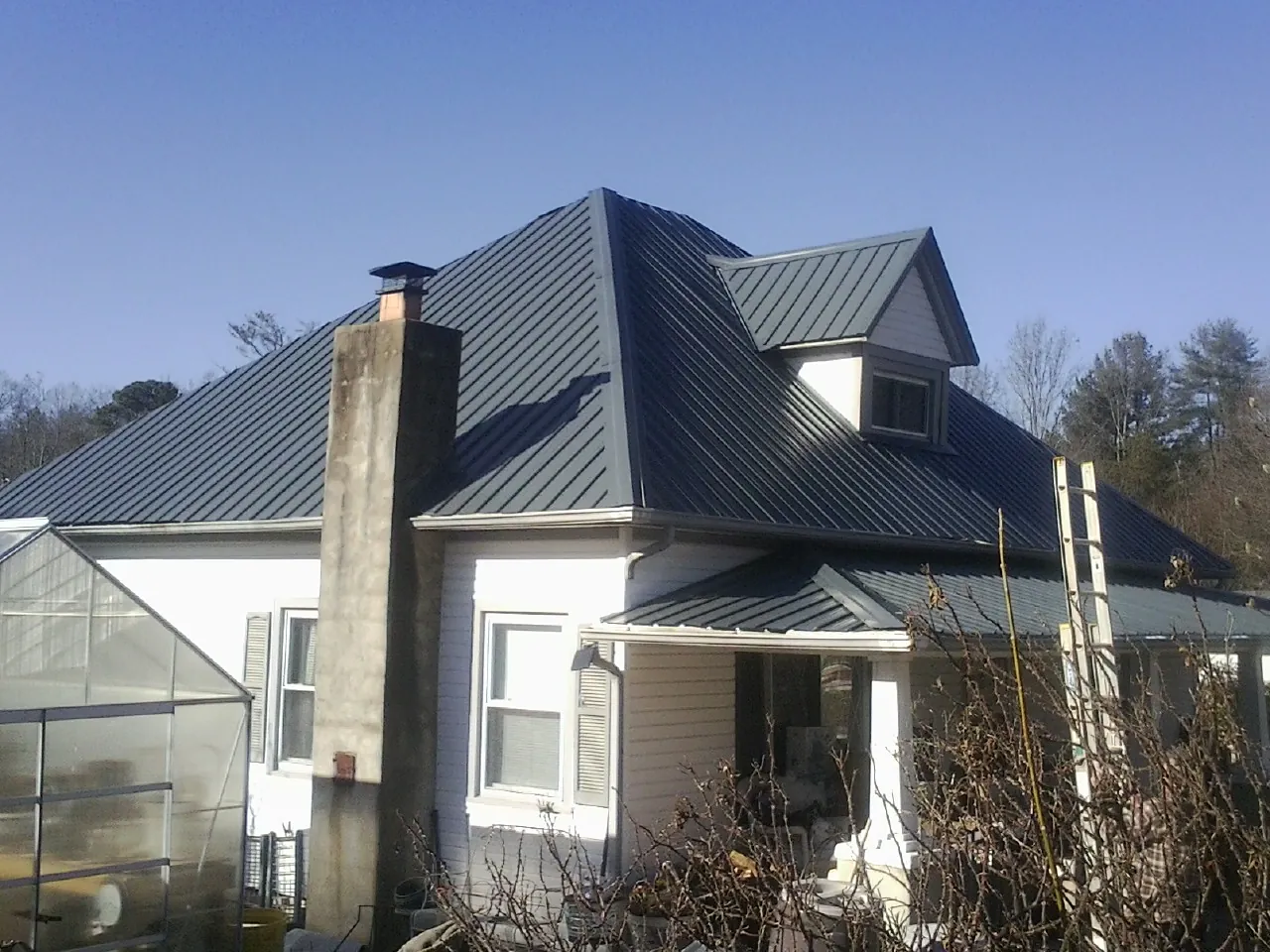 Dark blue standing seam metal roof on a white farmhouse with dormer — Slate & Tile Roof Repair by Roofing Brothers in Elkhart