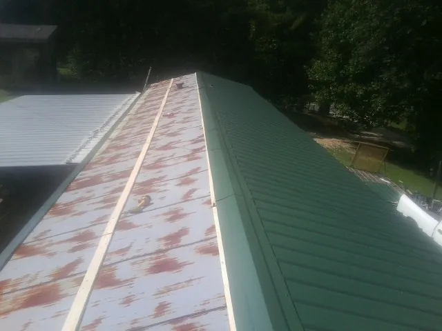 Old rusted panels beside newly installed green metal roofing — Wind Damage Roof Repair by Roofing Brothers in Elkhart