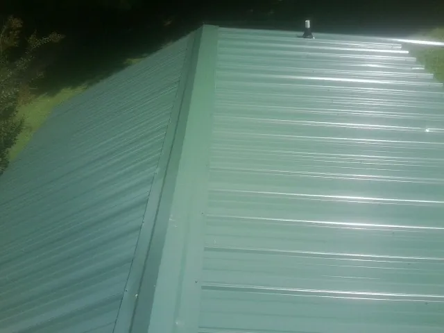 New green metal panels meeting at the ridge of a roof — Flat Roof Repair work by our crew in Elkhart