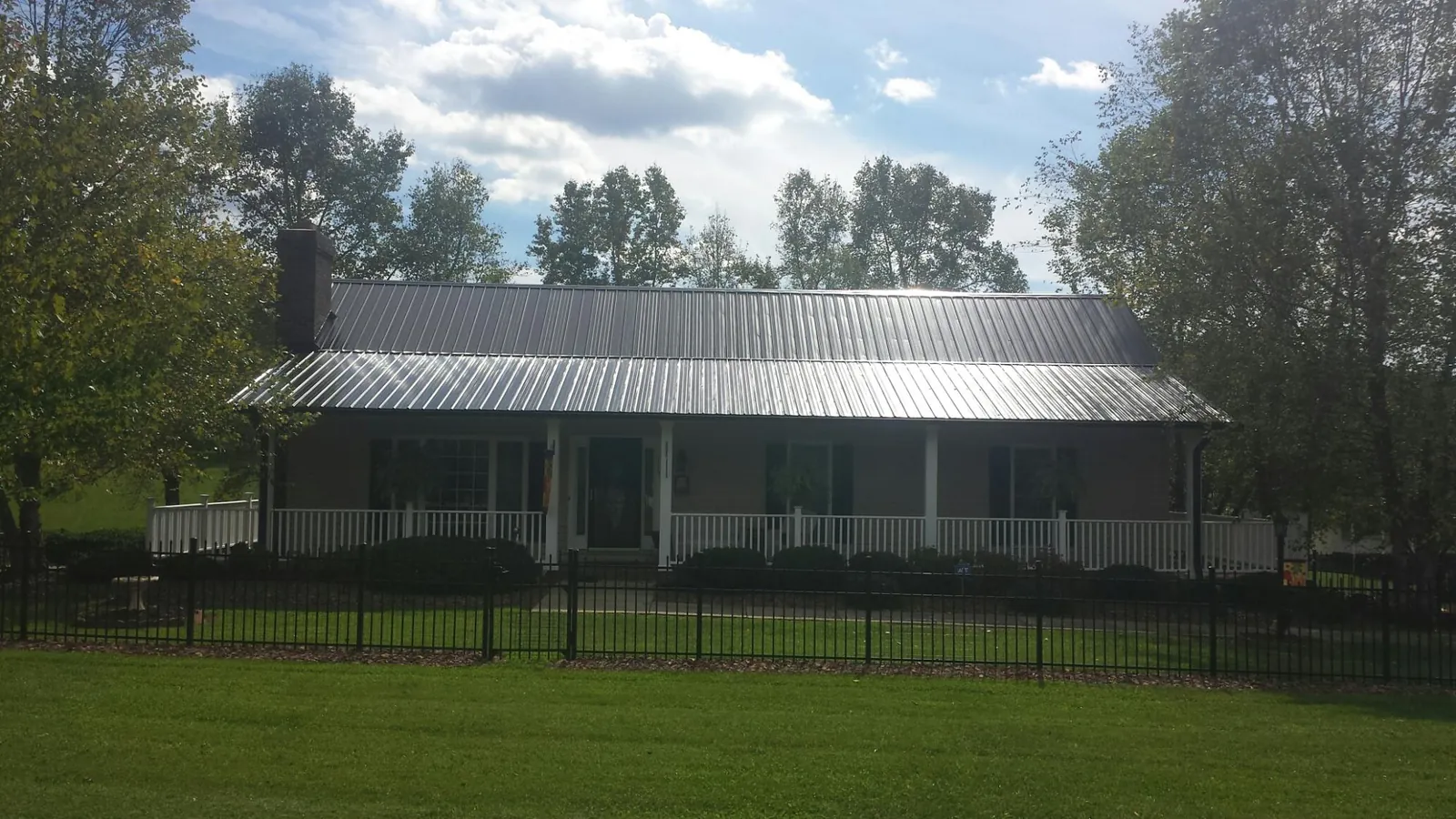 Gray metal roof on a brick ranch with a full width front porch — Gutter Guard Installation work by our crew in Elkhart
