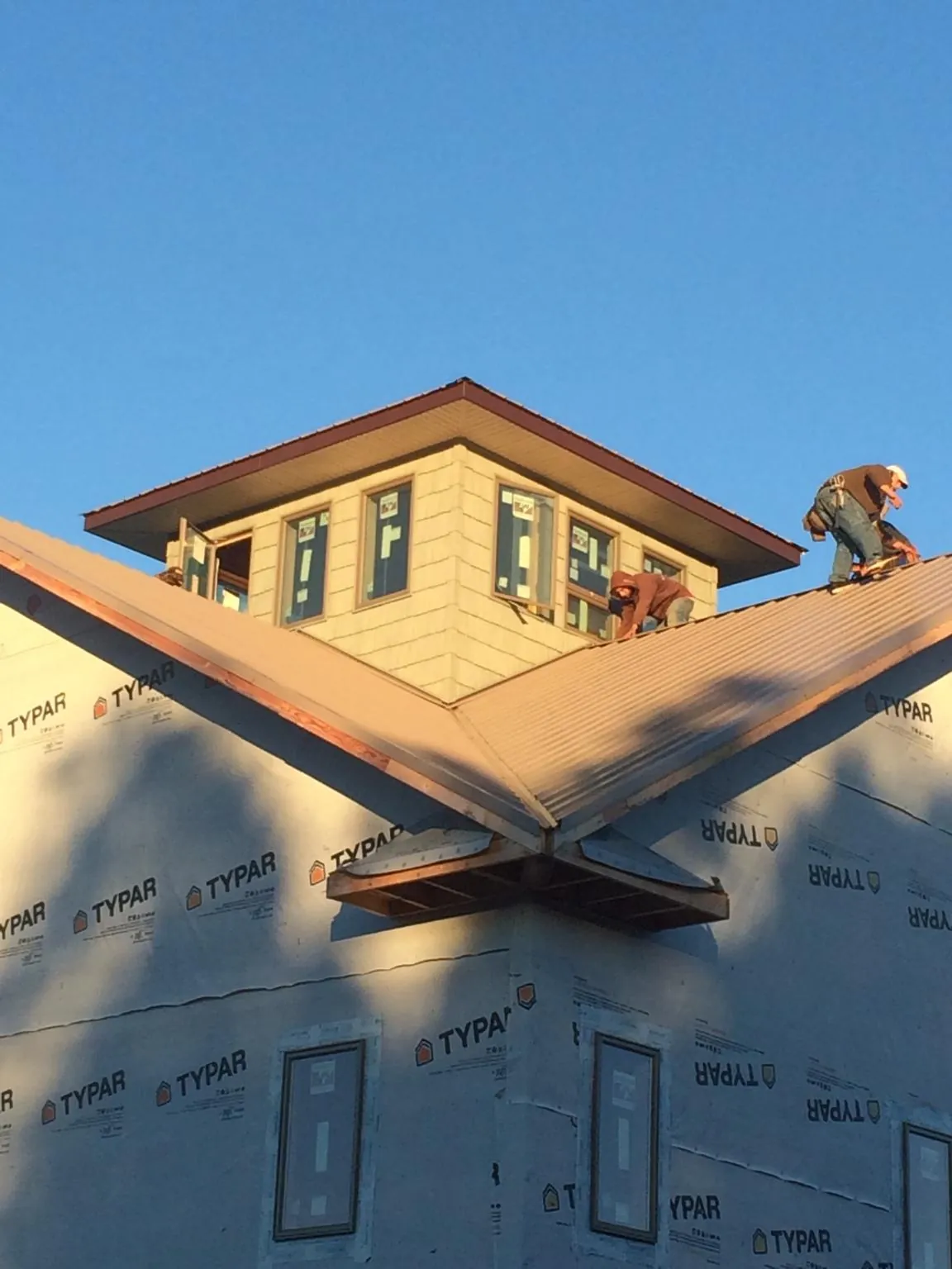 Roofers working around a rooftop cupola on a new metal roof at sunset — Roof Waterproofing in Elkhart by Roofing Brothers